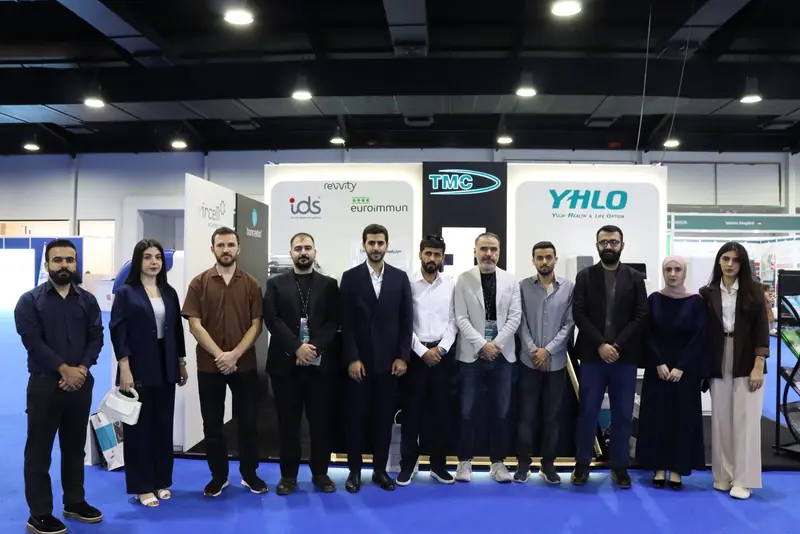 Eleven TMC team members standing in a row in front of the stand