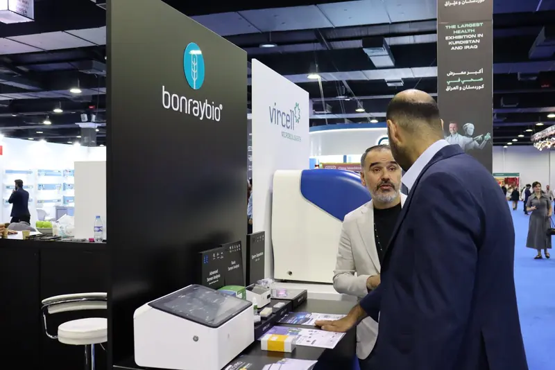 Staff member explaining a LensHooke analyser and kits on the Bonraybio counter to a visitor