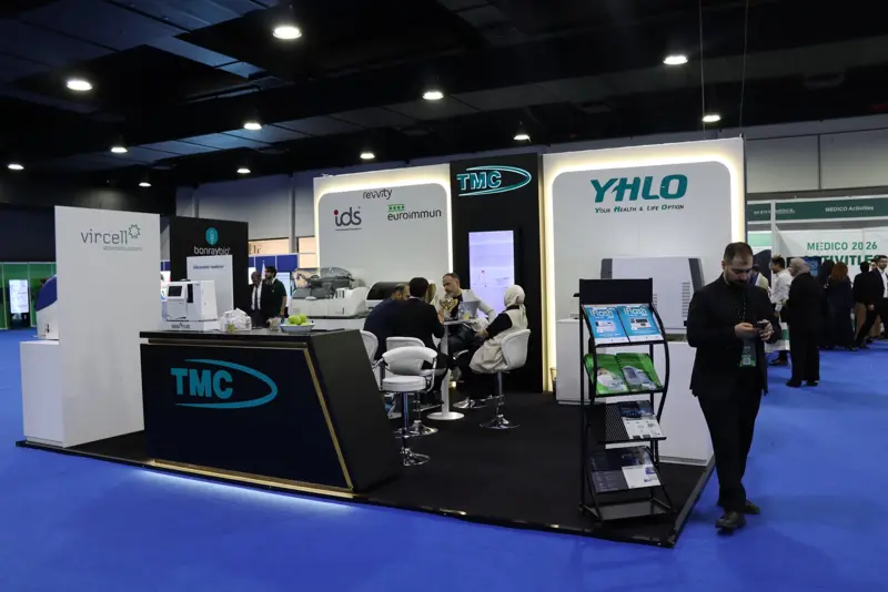 Wide view of the TMC stand with visitors at the meeting tables and the YHLO wall