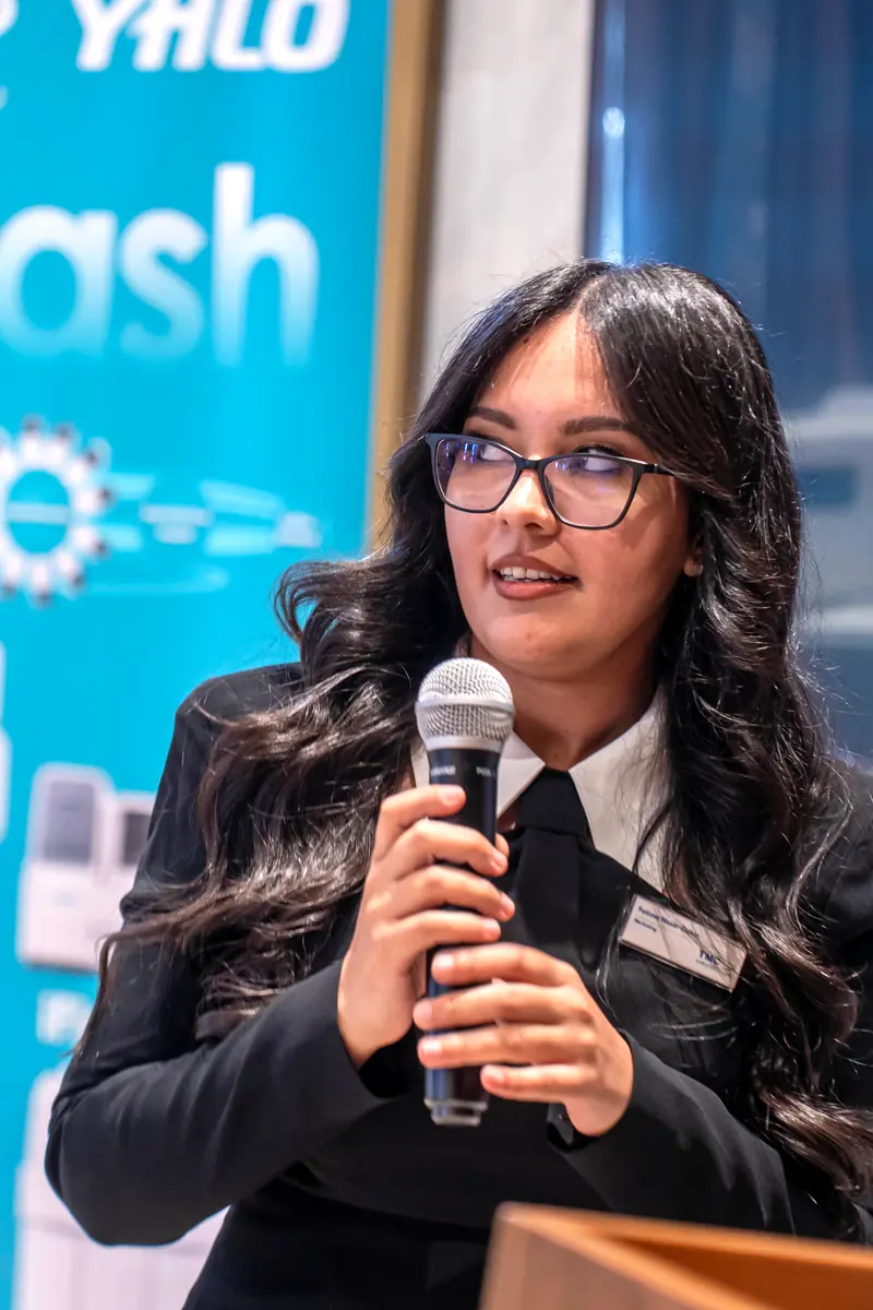 Woman in glasses speaking into a microphone in front of an iFlash banner