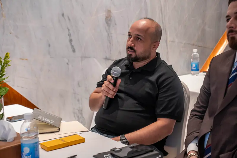 Seated attendee in a black shirt asking a question into a microphone