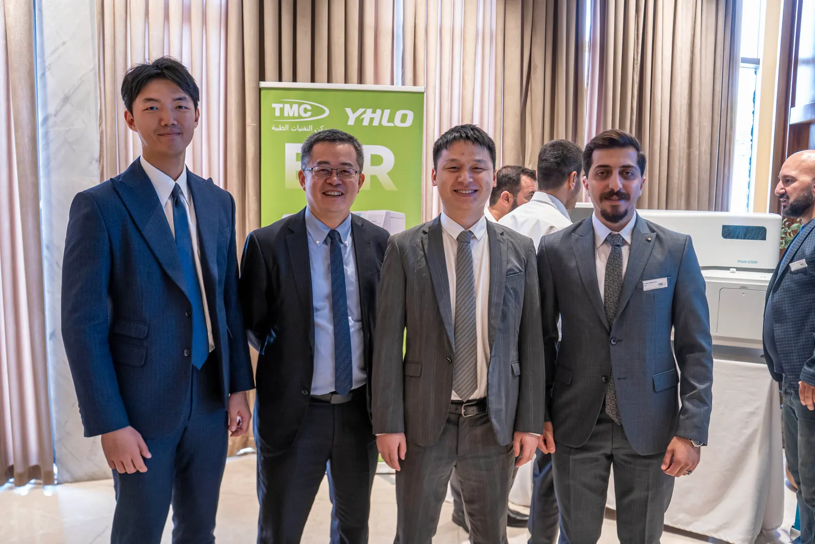 TMC team members with guests from YHLO in front of an ESR banner and an analyser